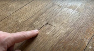 経年劣化によりひび割れや色あせが発生したフローリングの表面